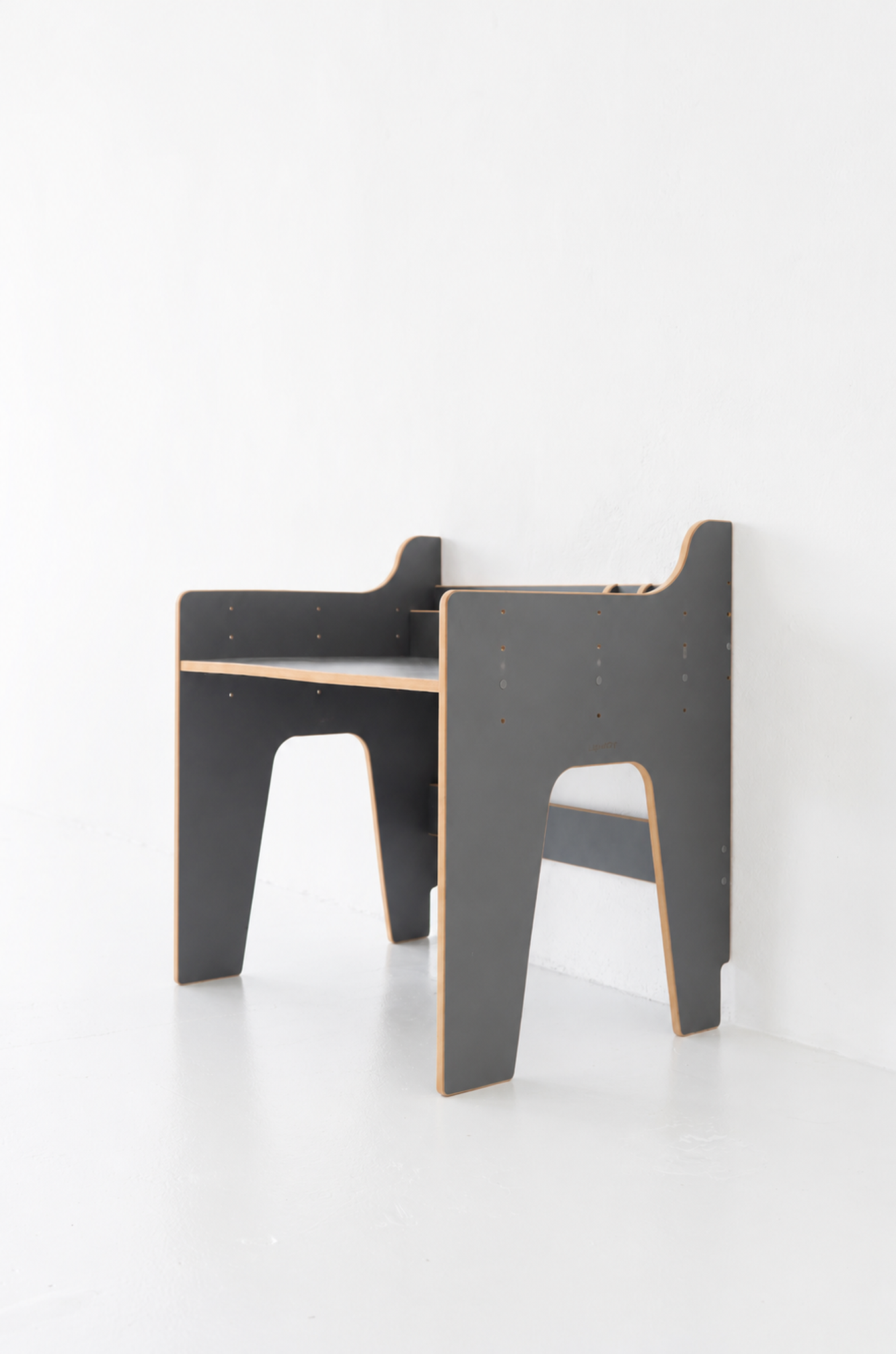 Deux tables d’étude modernes au design minimaliste, côtés noirs et contours bois, alignées près d’un mur blanc. Comment développer l'autonomie d'un enfant est évoqué indirectement par le cadre simple.