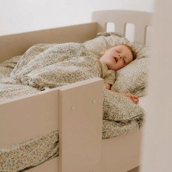 Enfant endormi dans un lit cabane en bois blanc, couvert d’une housse à motif floral, repos paisible. pourquoi lit cabane pas montessori