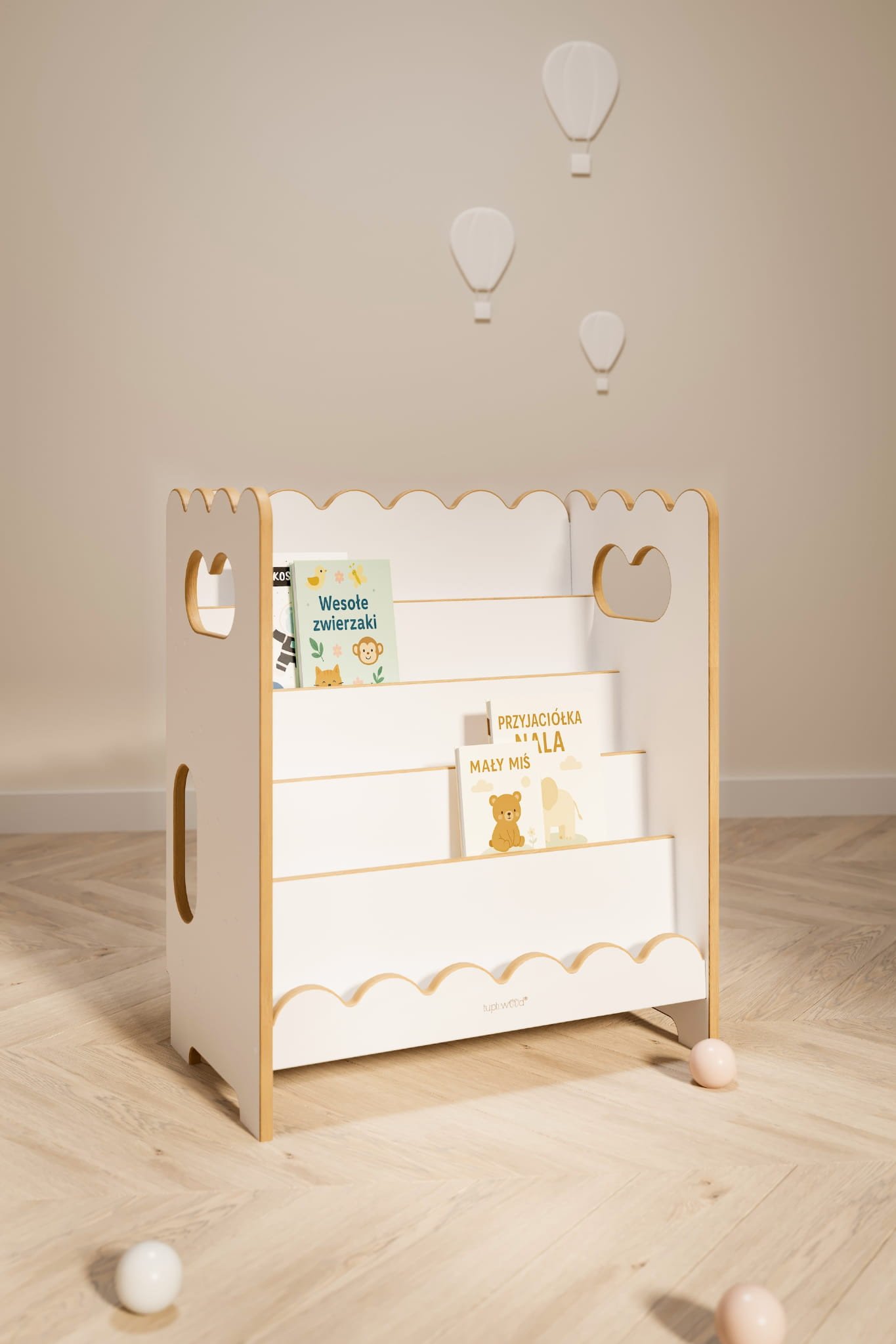 Petit meuble en bois clair avec marches et bords décoratifs, rempli de livres pour enfants; éléments de décoration suspendus au plafond.