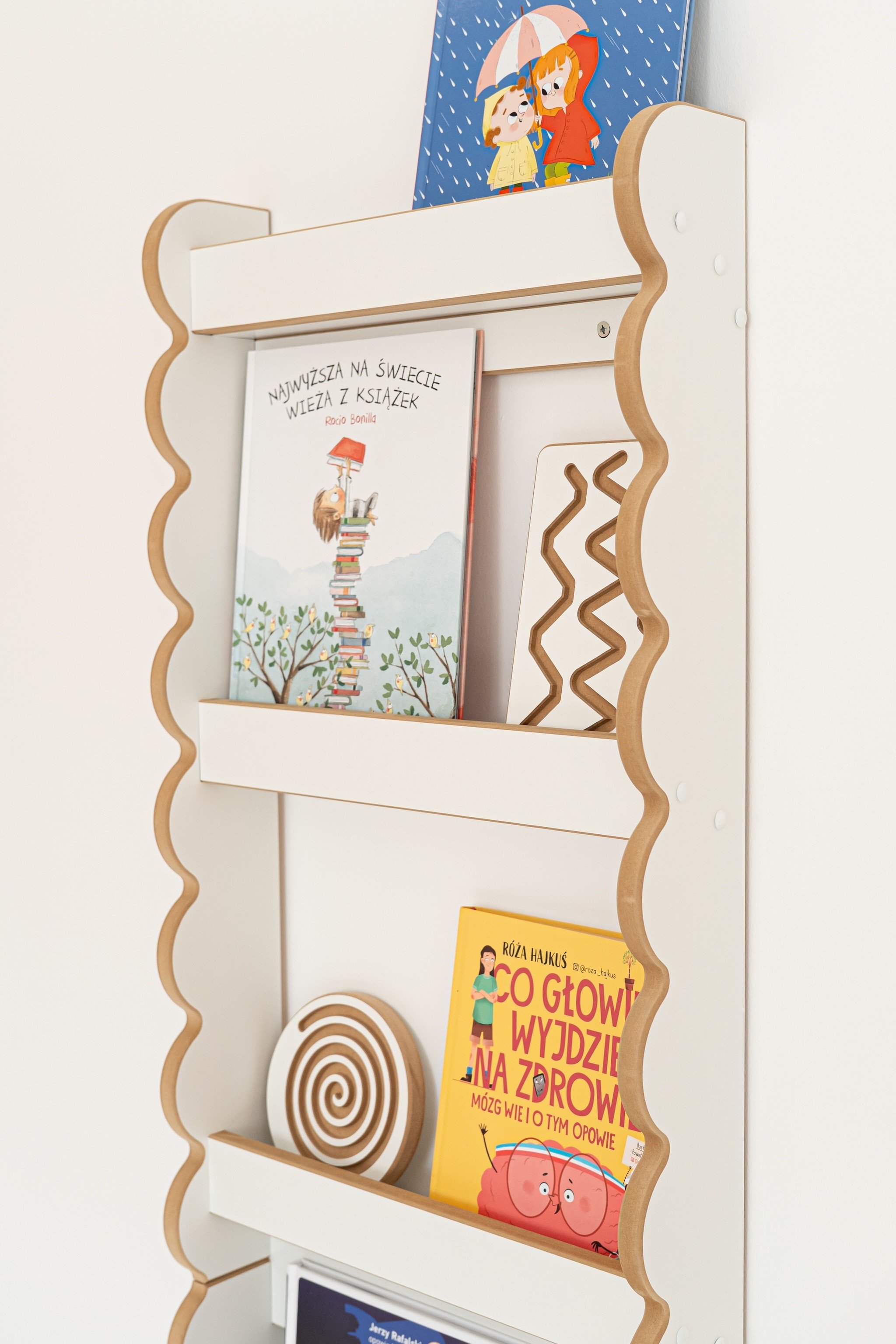 Rangement livres enfant accessible avec étagères frontales et rangements à portée demain, livres colorés sur une bibliothèque murale.